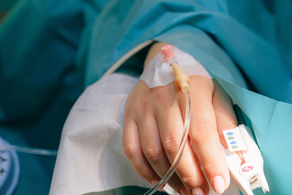 Close-up of a patient's hand with an IV catheter and medical tubing attached during hospital treatment.