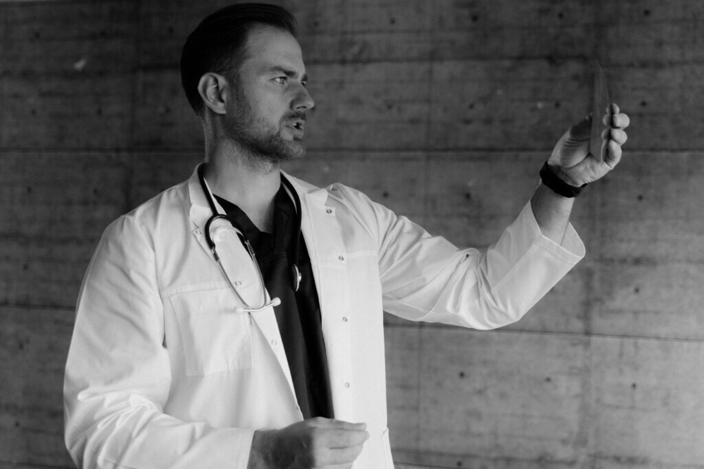 Male doctor reviewing a medical image while standing in a clinical setting.